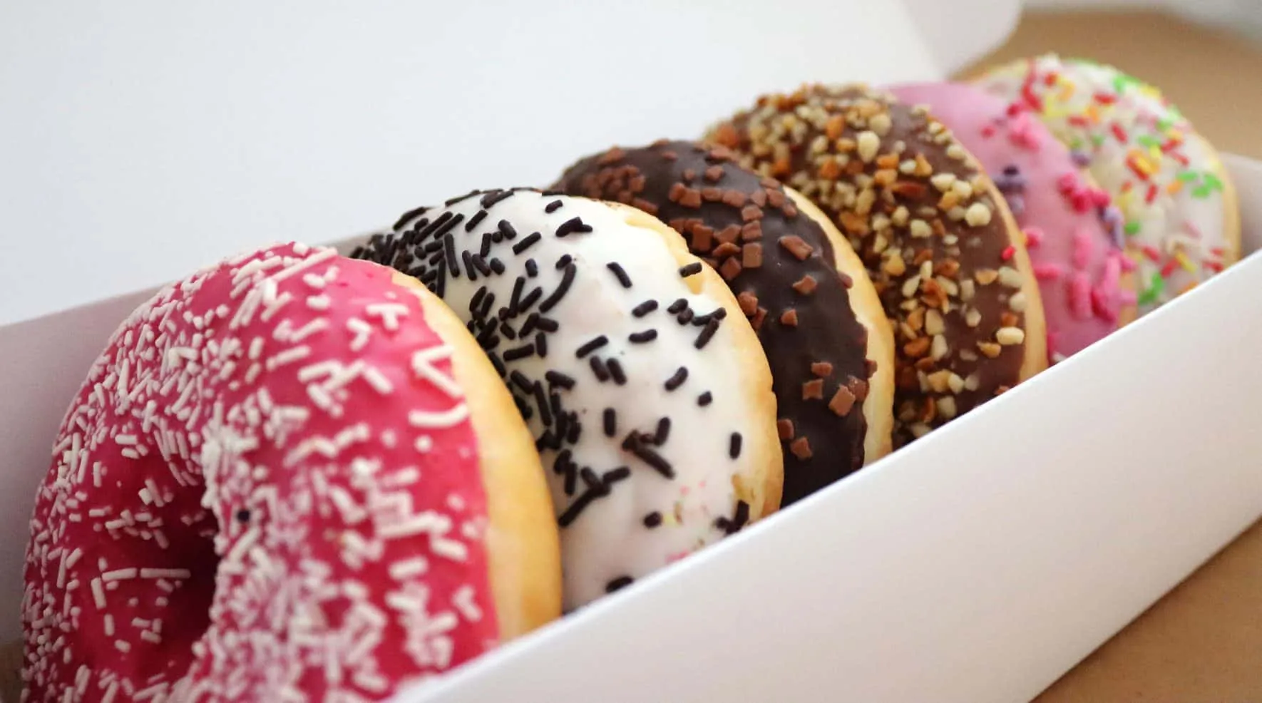 Reihe bunt glasierter Donuts in einer Schale