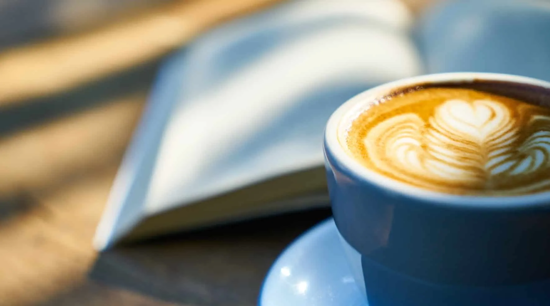 Blaue Tasse Cappuccino mit Latte-Art vor einem aufgeschlagenen Buch – Java 17 Features
