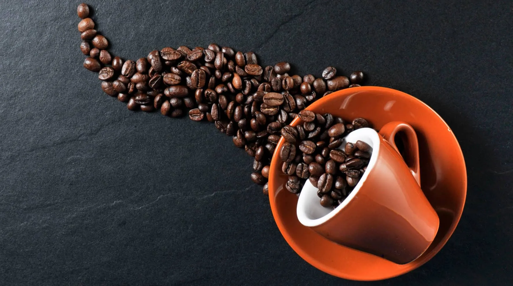 Umgekippte orangefarbene Tasse, aus der sich eine Spur Kaffeebohnen ergießt – Java 20 Features