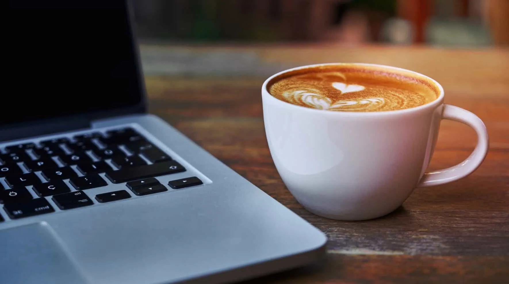 Tasse Cappuccino neben einem aufgeklappten Laptop – Java 22 Features