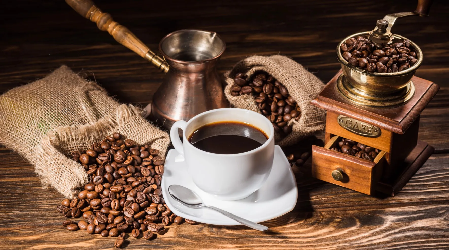 Cup of black coffee next to a coffee grinder, a cezve, and coffee beans on a wooden table – Java 9 Features