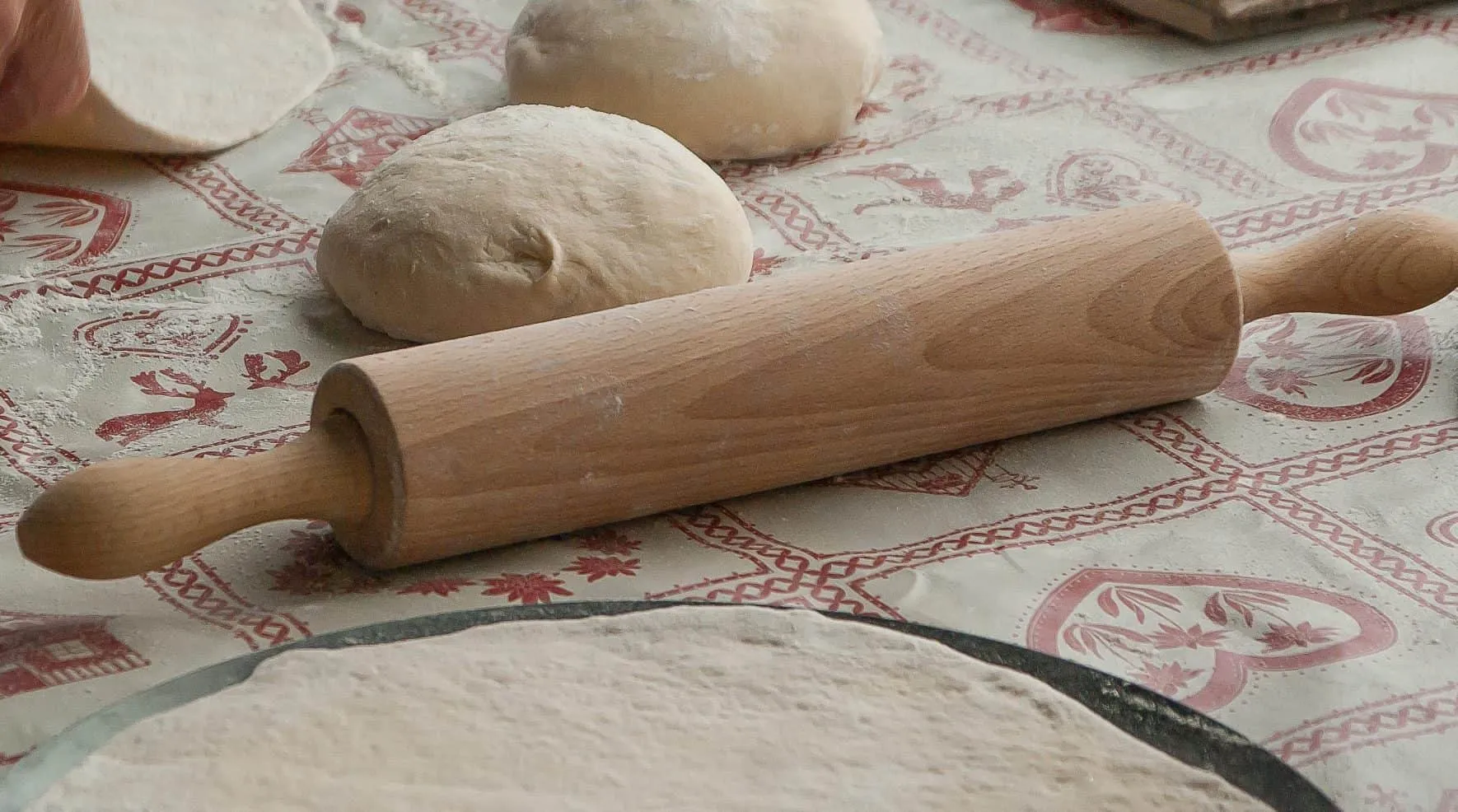 Balls of dough and a rolling pin on a floured cloth