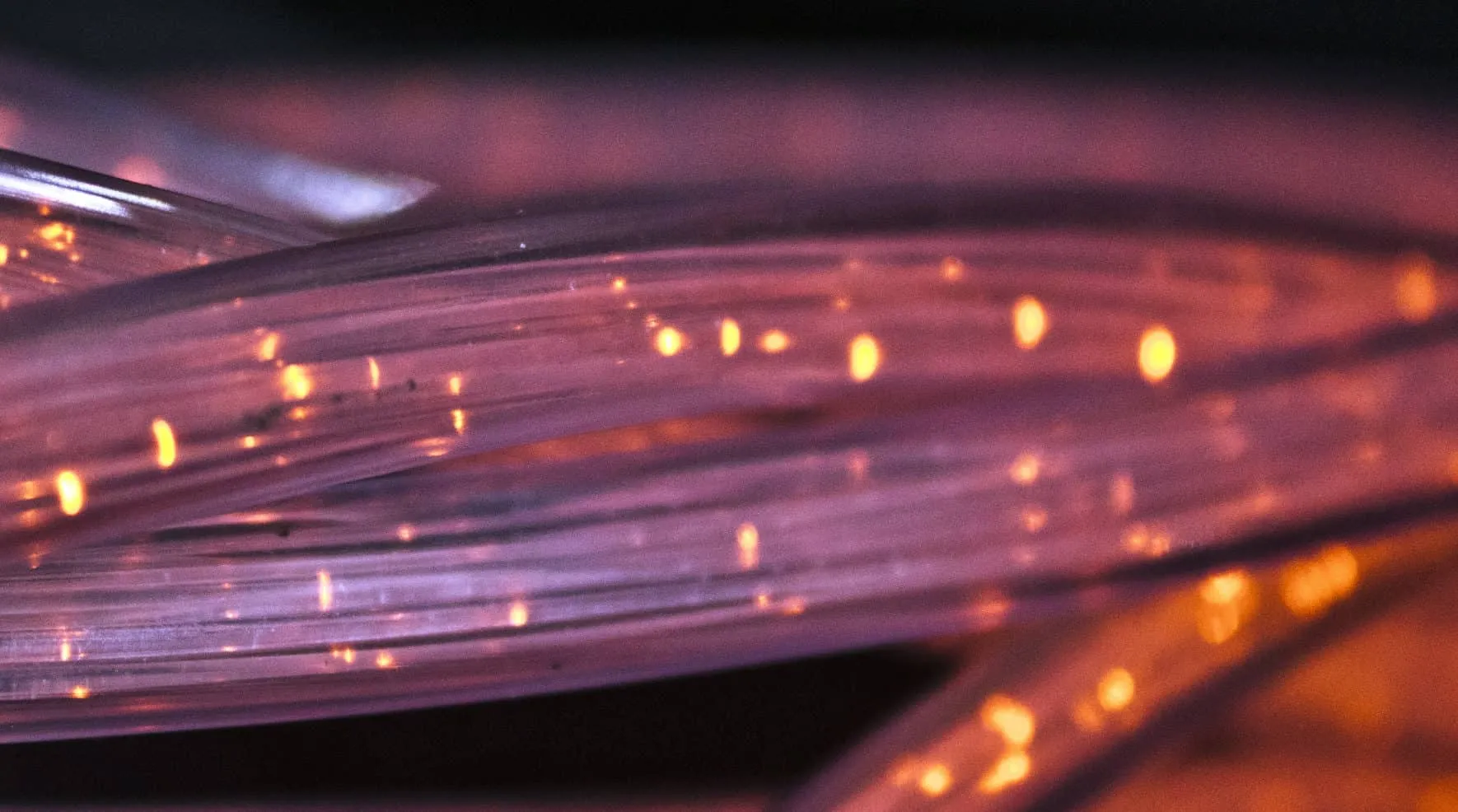 Bündel von Glasfasern, in denen orangefarbene Lichtpunkte laufen