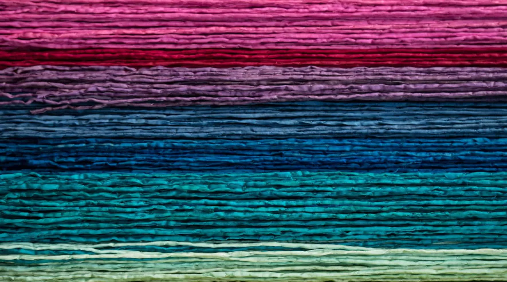 Stacked skeins of yarn in pink, blue and green
