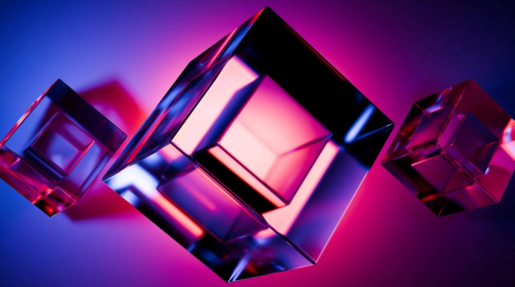 Three translucent glass cubes, glowing pink and blue in the dark