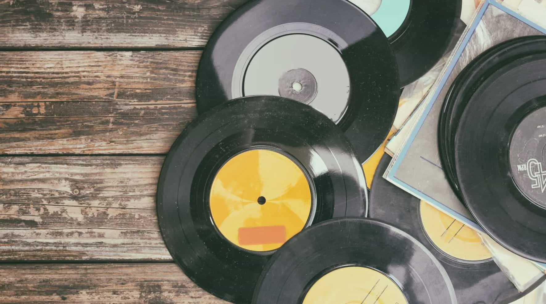 Vinyl records spread out on a wooden table