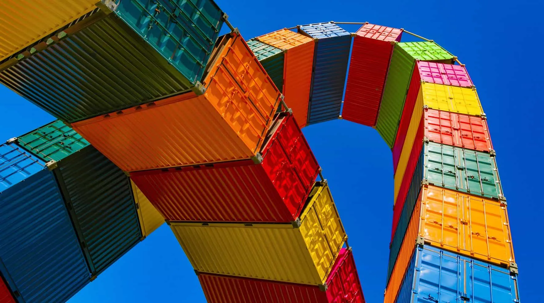 Colorful shipping containers stacked high against a blue sky