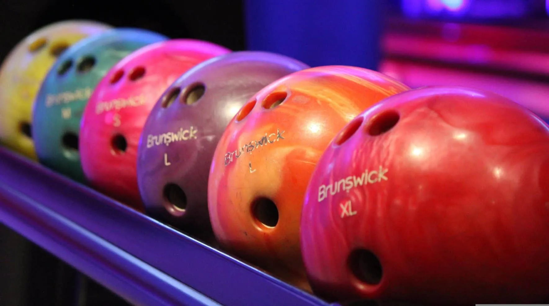 Bowling balls in various colors on the ball return
